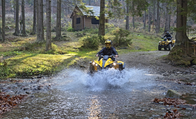 2 people riding quads in forest